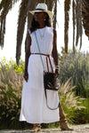 Woman standing outside wearing the turquoise crossbody, white pearl classic strap as a bracelet, fancy tiger's eye spurs and tiger's eye hat band